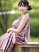 A woman in a pink dress sitting on a wooden bench.