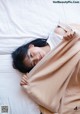 A woman laying on a bed covered in a blanket.