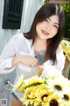 A woman holding a basket full of sunflowers next to a bike.