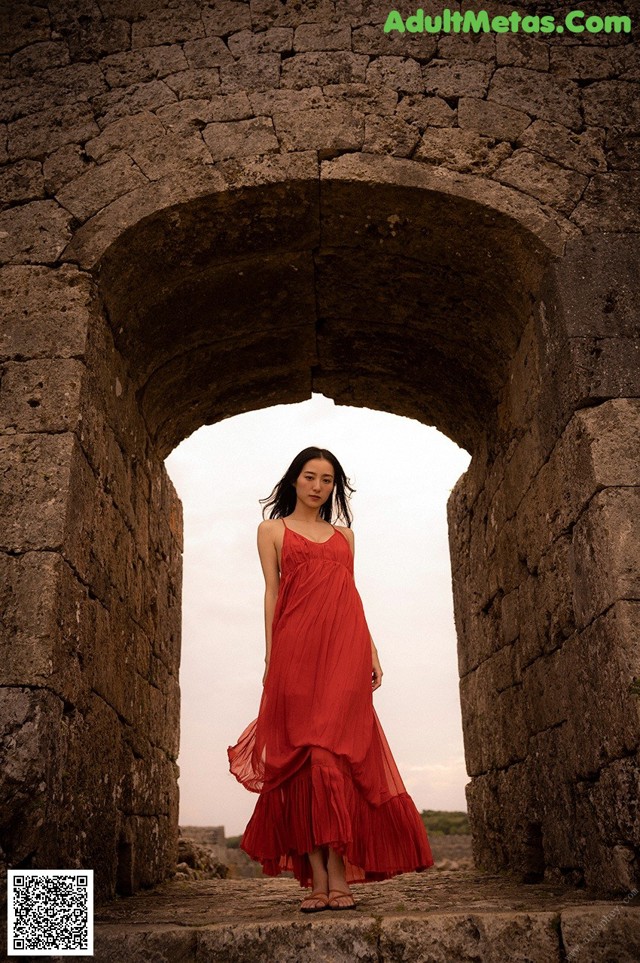 A woman in a red dress standing in an archway.