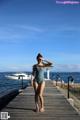 A woman in a blue bathing suit standing on a dock.