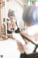 A woman in a maid outfit looking at herself in a mirror.