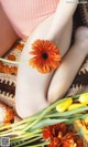 A close up of a woman's legs with a flower in her hand.