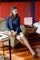 A woman sitting on a chair in a hotel room.