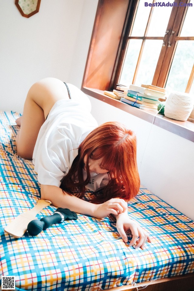 A woman laying on top of a bed next to a window.