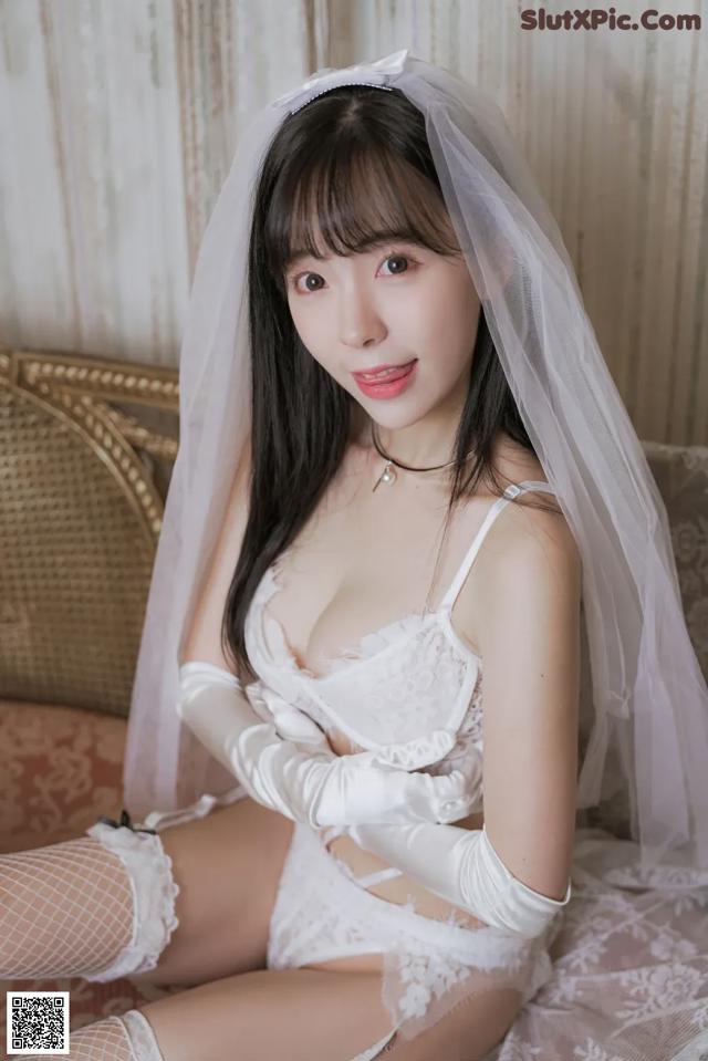 A woman in a wedding dress and gloves sitting on a couch.