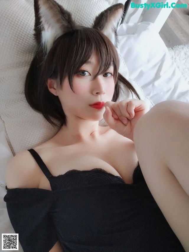 A woman in a black dress laying on a bed.