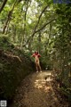 A naked woman standing in the middle of a forest.